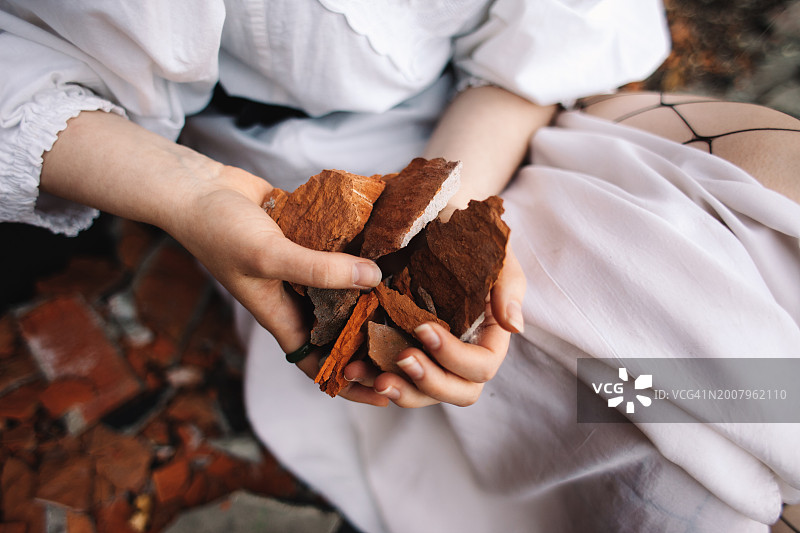 年轻女人坐在废墟中拿着破砖图片素材