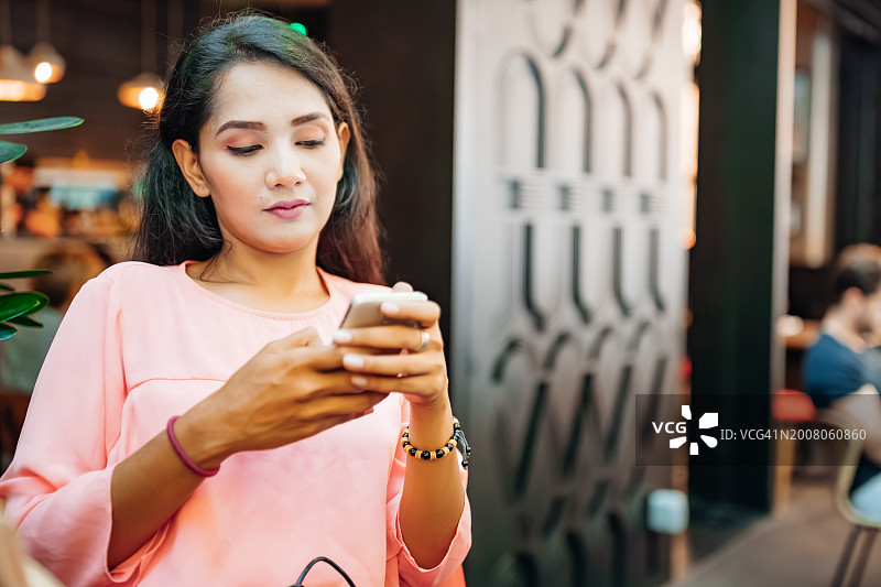 在餐厅入口使用手机的亚洲女人图片素材