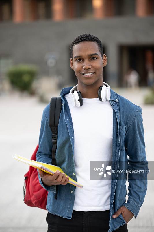 英俊的男学生背着背包拿着笔记本图片素材