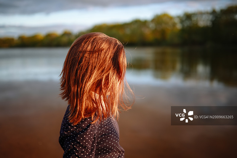 宁静中的少女：在湖边欣赏日落，沐浴大自然的温暖图片素材