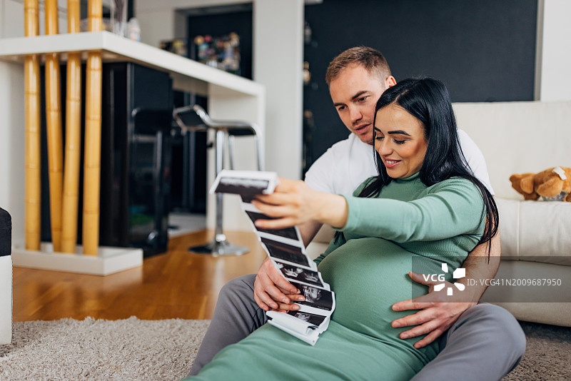 怀孕的妇女和她的丈夫正在看他们即将出生的婴儿的超声波图像图片素材