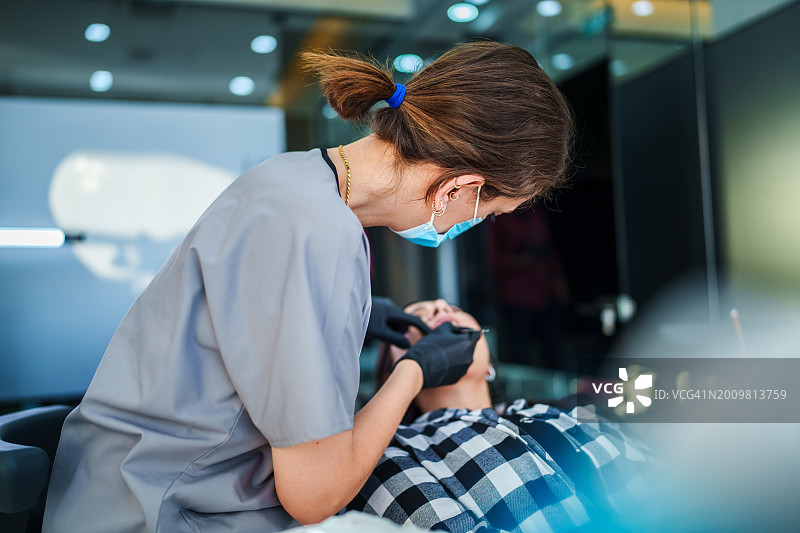 系列：女牙医为躺在牙椅上的女患者进行种植治疗图片素材
