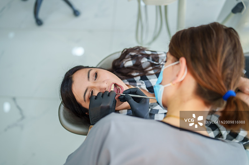 系列：女牙医为躺在牙椅上的女患者进行种植治疗图片素材