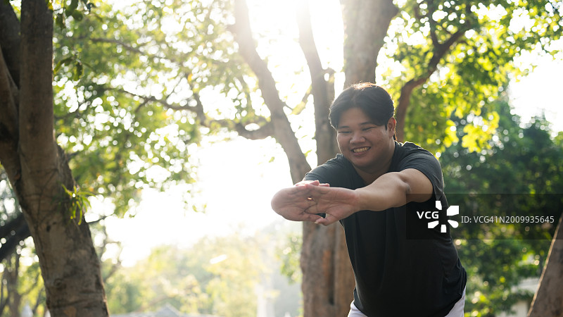 在公园锻炼前伸展的快乐的肥胖男子。运动和健康生活方式概念。图片素材