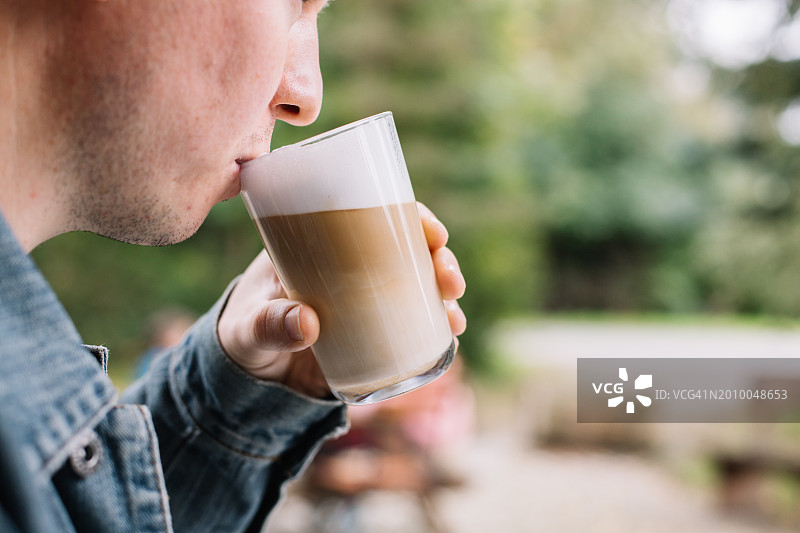 男人在街边咖啡馆喝拿铁玛奇朵咖啡的特写图片素材