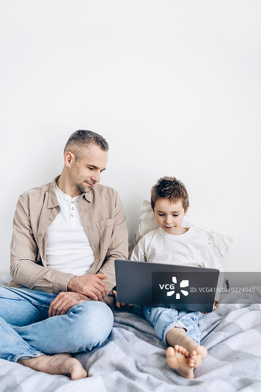 年轻的白人父亲和儿子在家中使用笔记本电脑图片素材