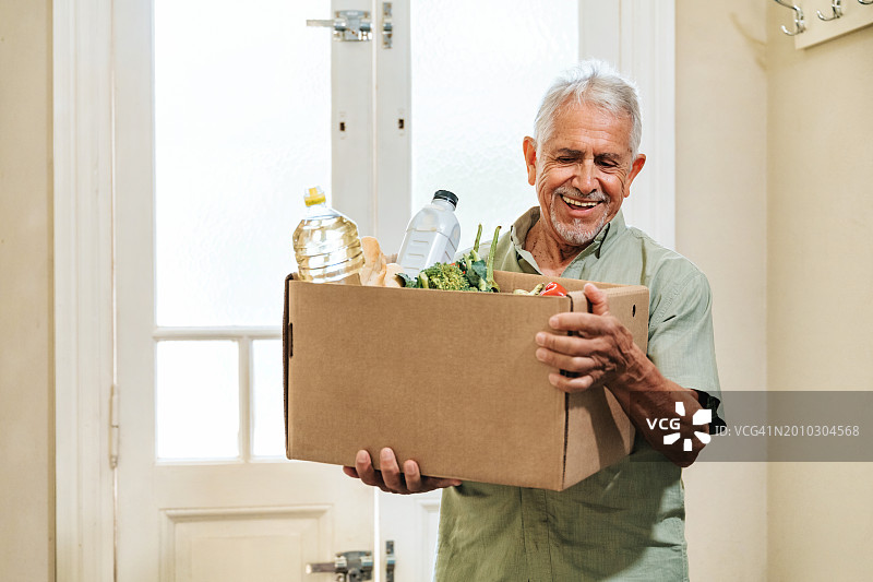 快乐老年男人提着日用品箱图片素材