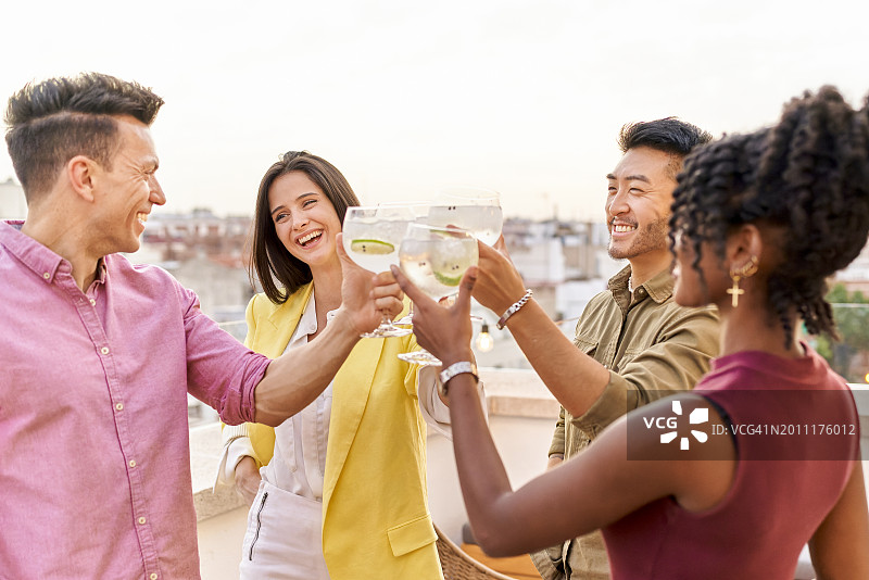 朋友们在公寓露台上庆祝工作晋升，日落时分举杯敬酒图片素材