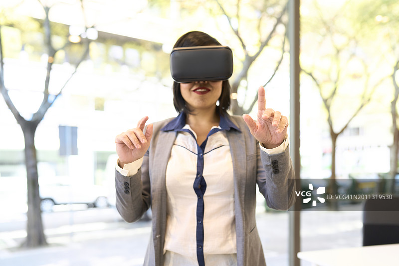 办公室里戴VR眼镜微笑的女性肖像图片素材