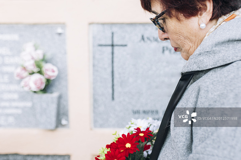 老年女性在墓地葬礼上手捧鲜花图片素材