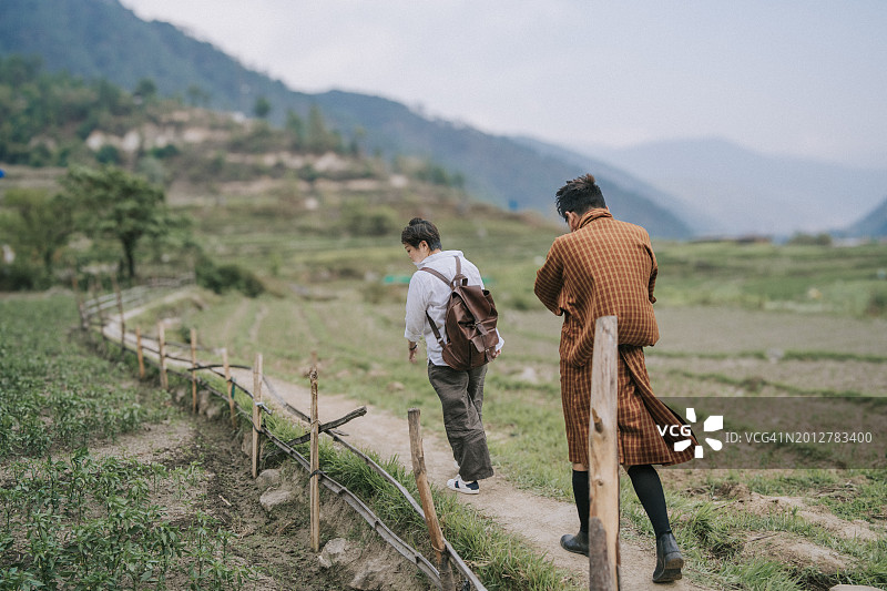不丹导游和亚洲女游客在乡村稻田漫步图片素材