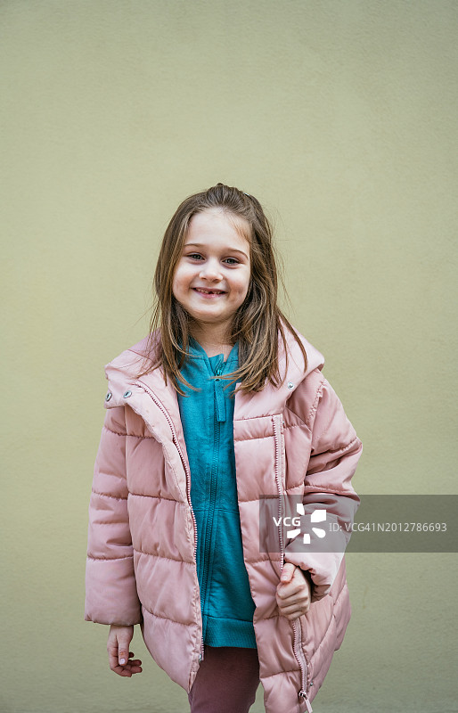 在柔和的墙壁前摆姿势的可爱的七岁女孩图片素材