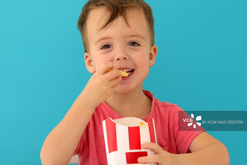 男孩在蓝色背景下吃东西的肖像图片素材