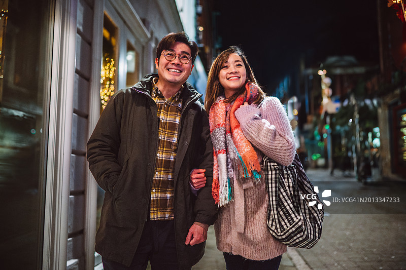 快乐的亚洲夫妇在街上享受晚餐后的散步图片素材