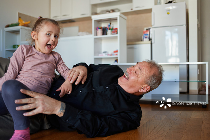 爷爷和孙女在客厅的地板上玩耍图片素材