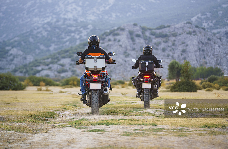 两位骑着摩托车在乡间小路上冒险的骑手图片素材