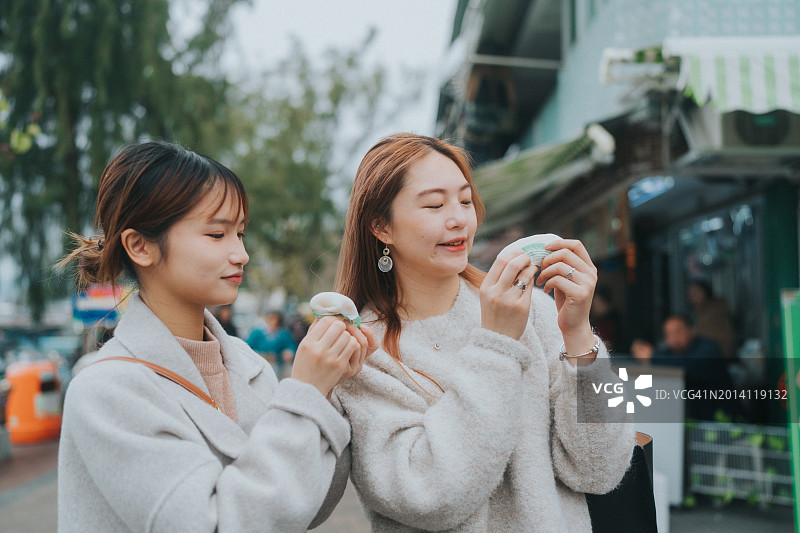 两位年轻的亚洲女性在香港充满活力的街道上探索图片素材