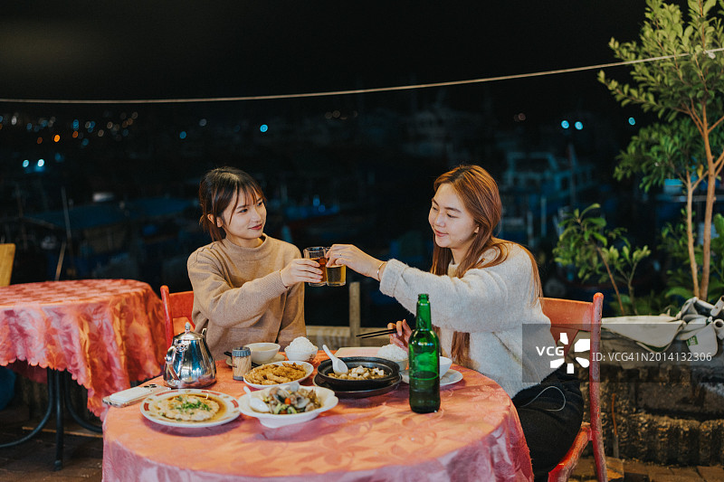 两位年轻的亚洲女孩在香港大排档享用晚餐图片素材