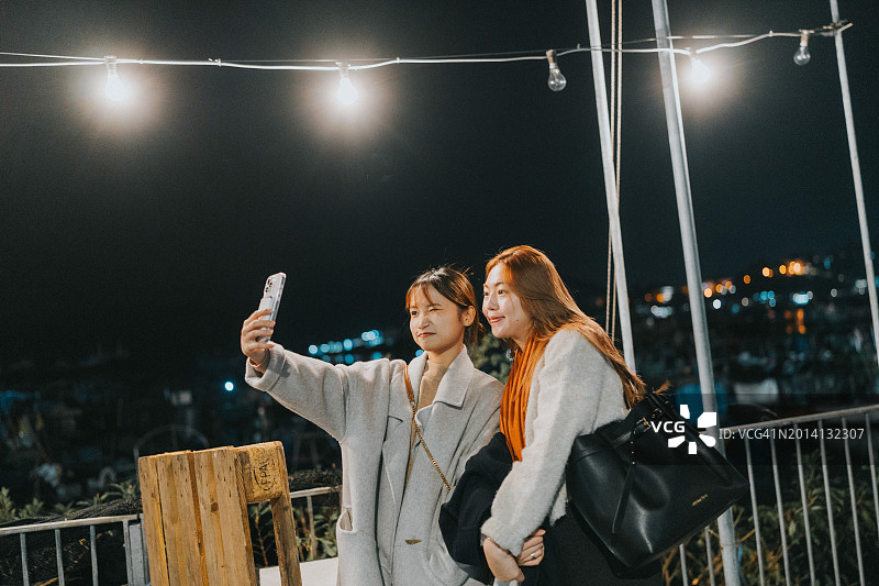 两位年轻的亚洲女孩在香港离岛长洲的夜空下自拍图片素材