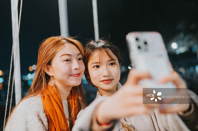 两位年轻的亚洲女孩在香港离岛长洲的夜空下自拍图片素材