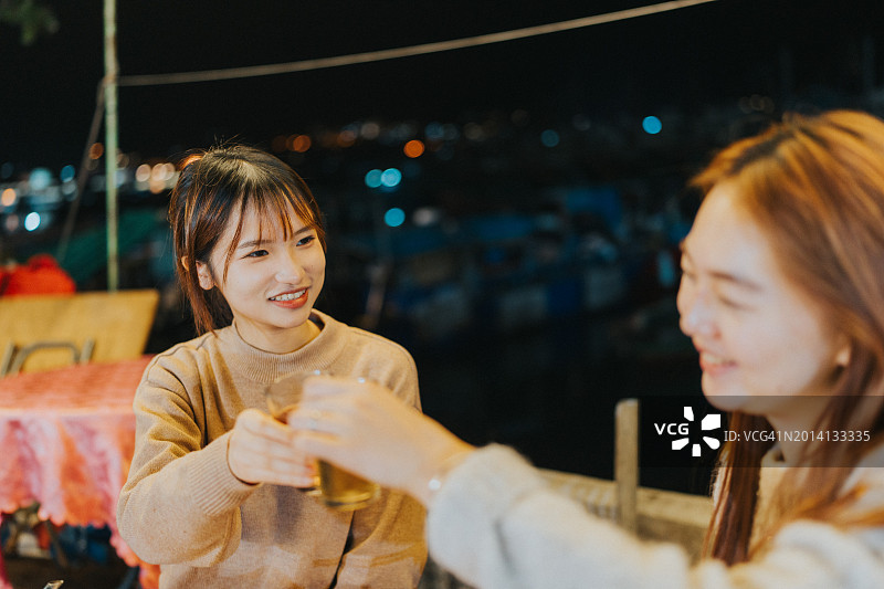 两位年轻的亚洲女孩在香港大排档享用晚餐图片素材