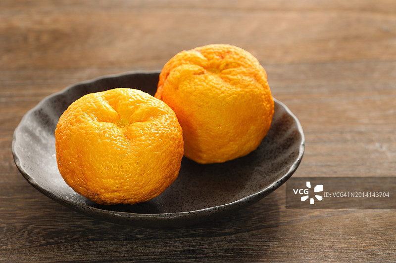 柚子果香浓郁，日式柑橘置于硬木地板背景小碗中图片素材