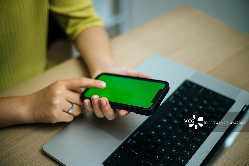 年轻的亚洲女软件工程师正在使用带绿屏的手机图片素材