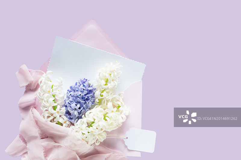 母亲节贺卡：优雅的风信子和白色鲜花，粉色薄纸包裹，淡紫色背景图片素材