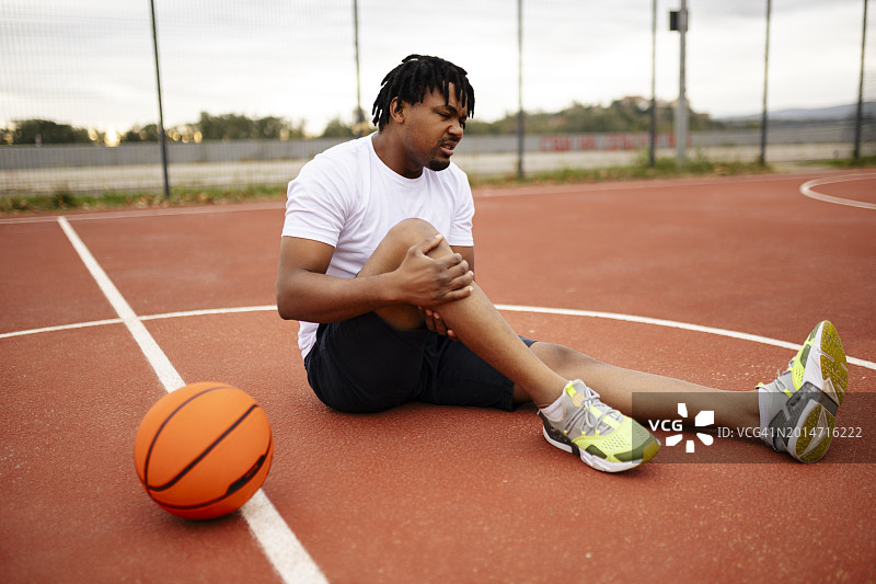 篮球运动员在球场上痛苦地抱着腿图片素材