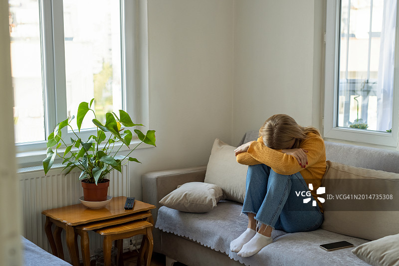 悲伤的女人坐在家里的沙发上图片素材