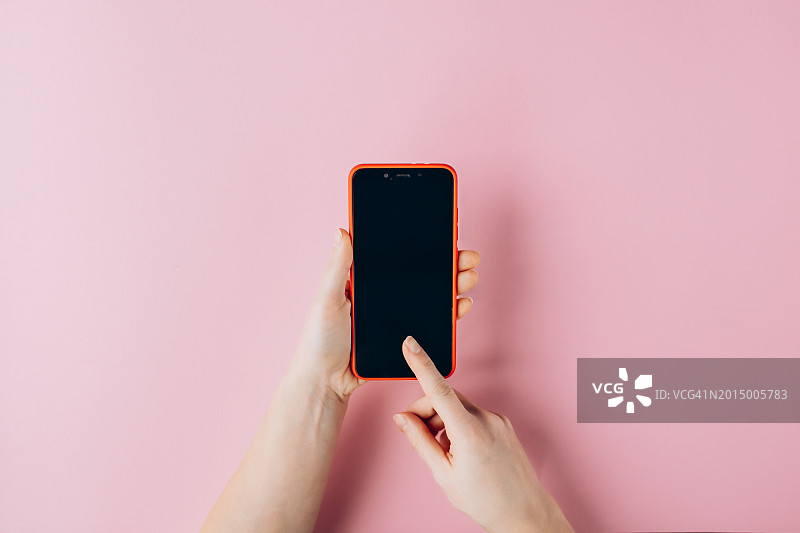 女人在粉色背景上使用智能手机特写图片素材