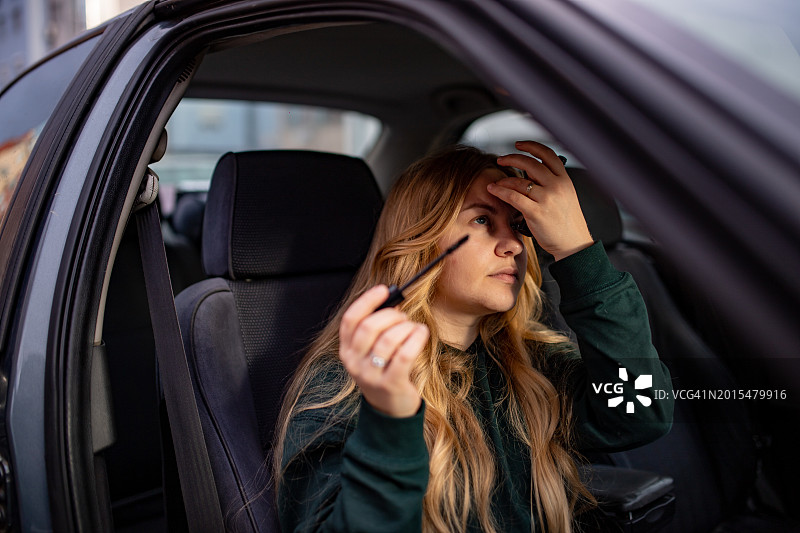 坐在车里涂睫毛膏的年轻女人图片素材