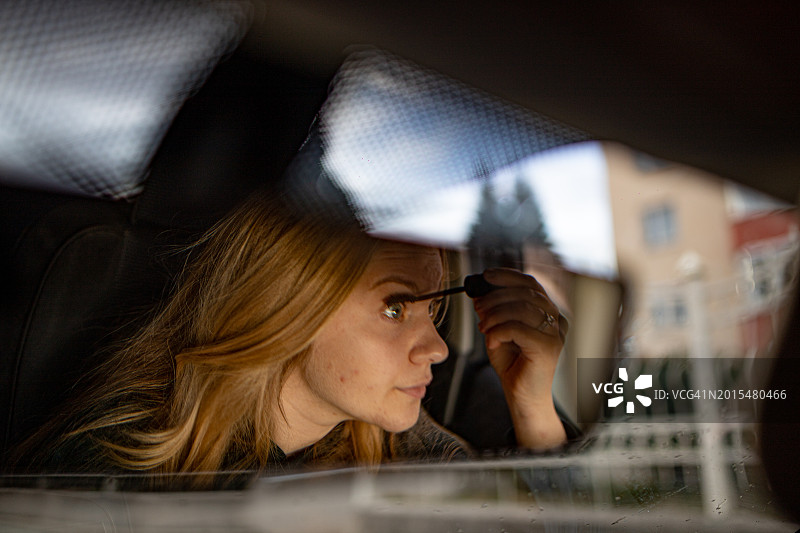 坐在车里涂睫毛膏的年轻女人图片素材