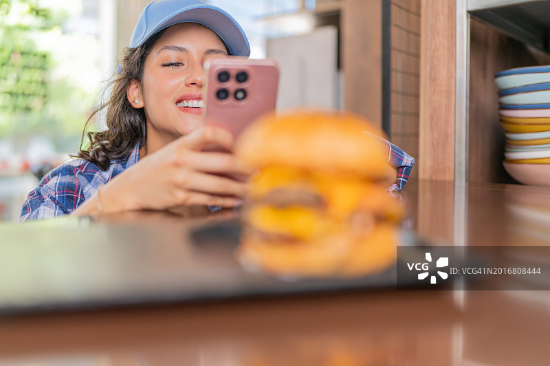 年轻女子拍摄汉堡照片分享图片素材