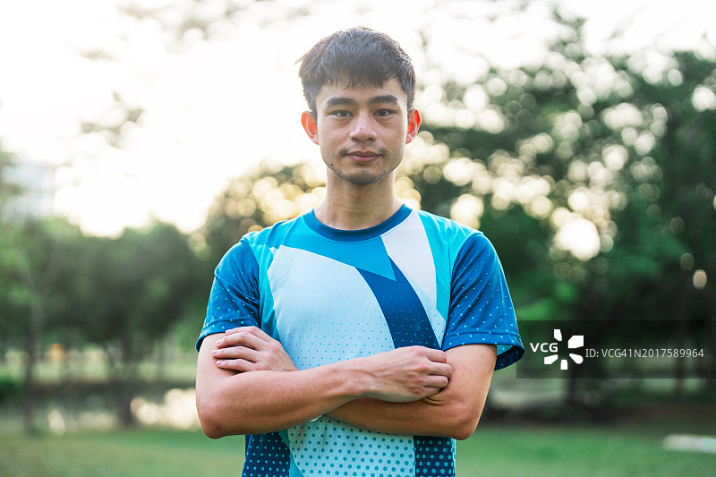 站在公园里，一位面带微笑的快乐亚洲青年男人图片素材