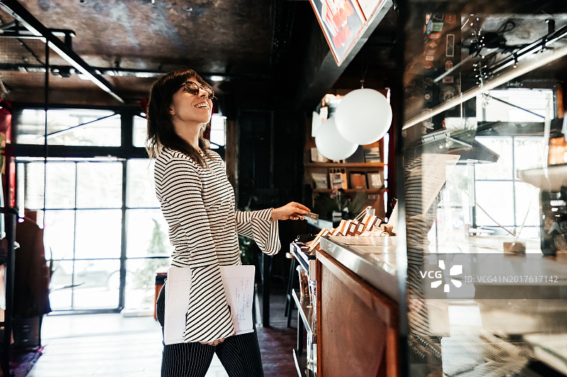 在咖啡店非接触式支付的年轻微笑的女人图片素材