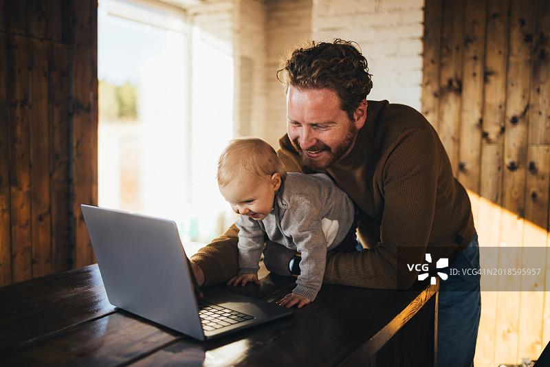 父子在温暖的房间里一起使用笔记本电脑图片素材