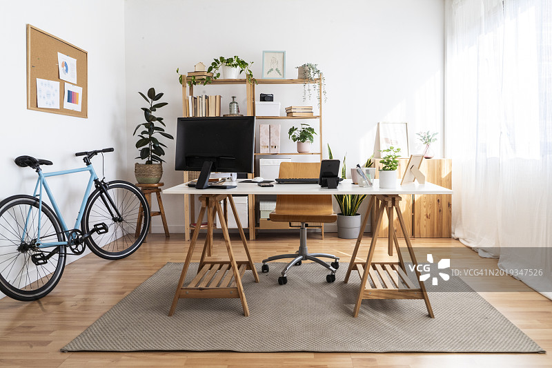 阁楼公寓中的现代小型办公室，配有桌子和自行车图片素材