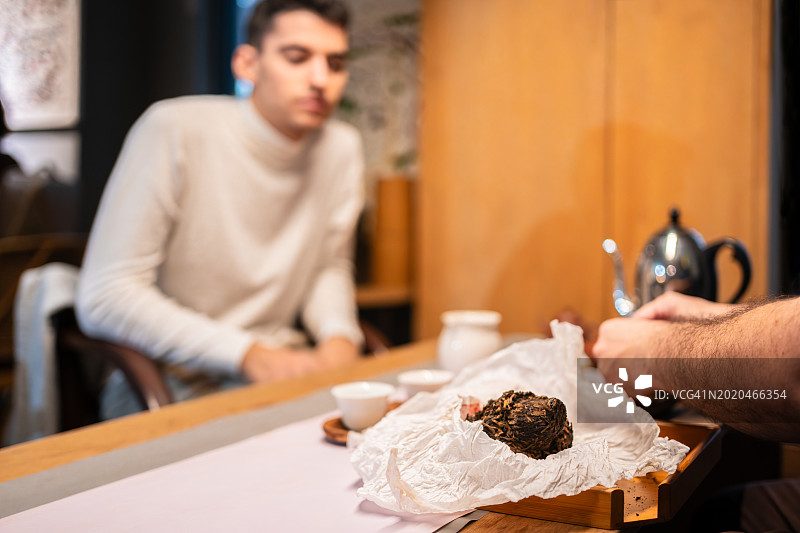 年轻旅行者在中国台湾学习茶道，焦点集中在茶叶上图片素材