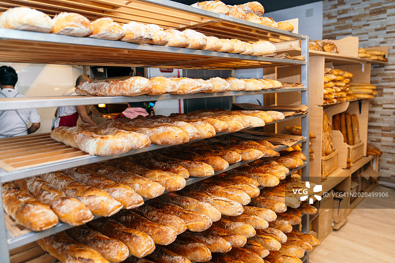 木制烘焙货架上展示的各种新鲜面包图片素材