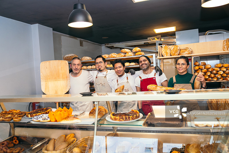 友好的面包店团队在柜台后展示新鲜面包图片素材