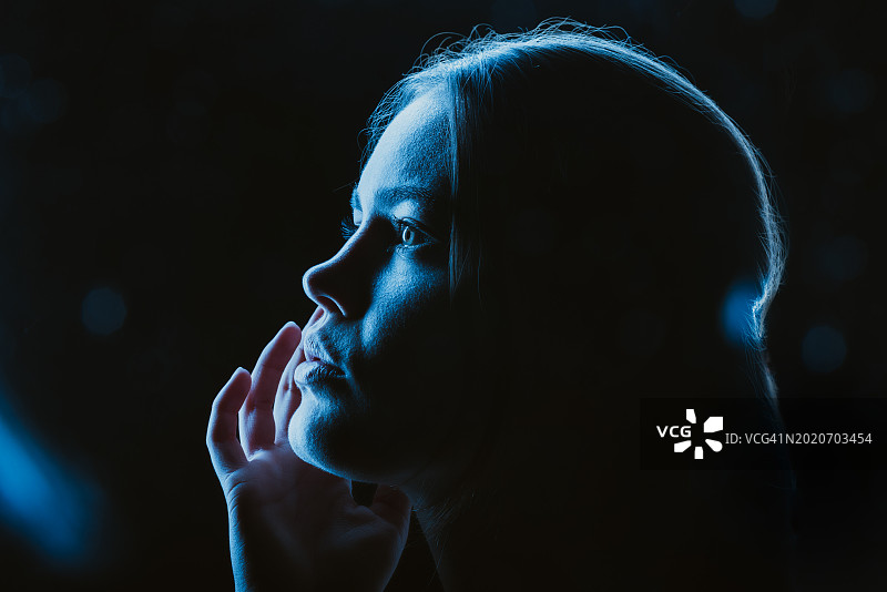 蓝色霓虹灯下的神秘女子侧面轮廓图片素材