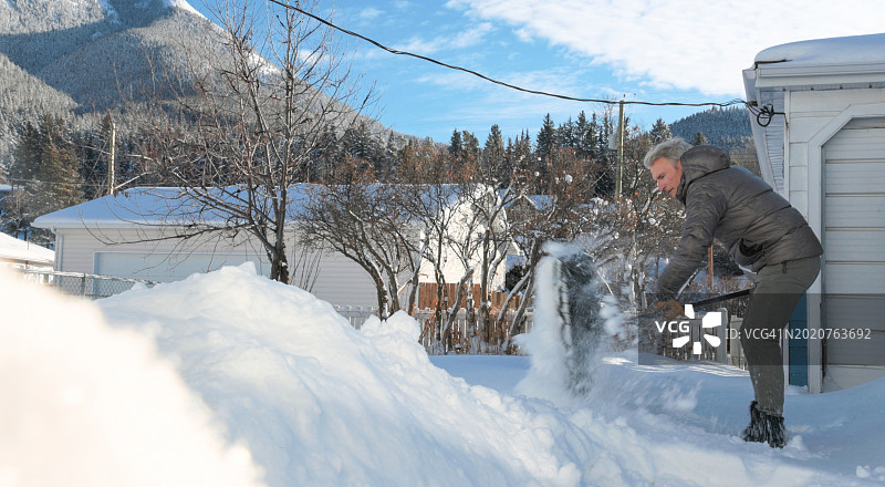 中年男人在人行道上铲雪图片素材