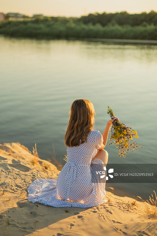 身穿连衣裙，手捧野花的金发女子剪影图片素材