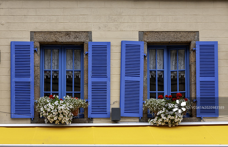 带有两扇窗户、蓝色窗框和蓝色百叶窗的房屋立面，法国布列塔尼罗斯科夫图片素材