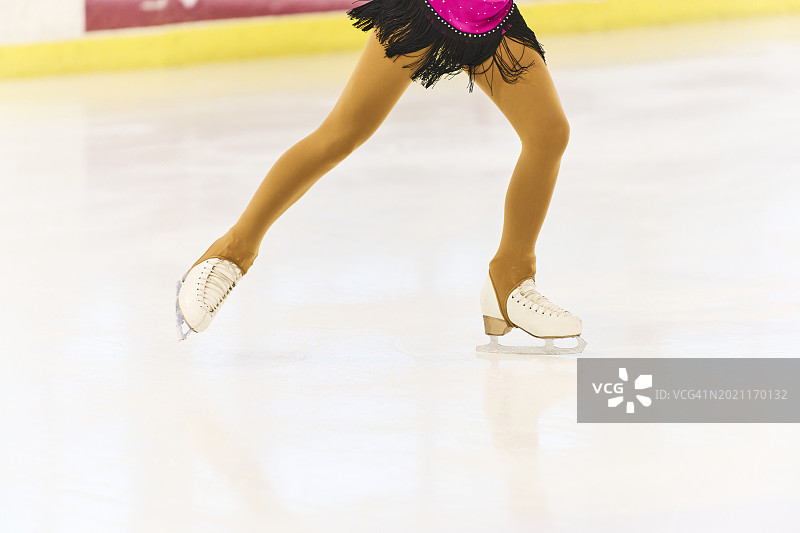 溜冰场上穿冰鞋的滑冰运动员的腿部，参加比赛的女性运动员图片素材