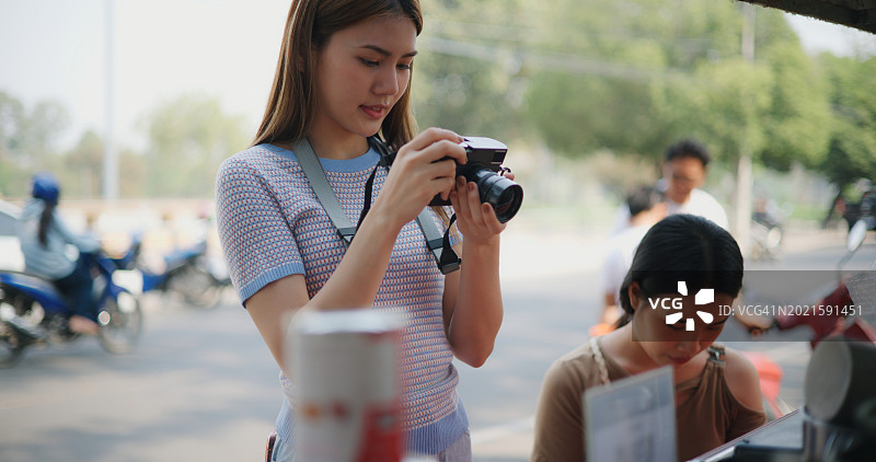 年轻女游客在乡村饮品店用相机拍照图片素材