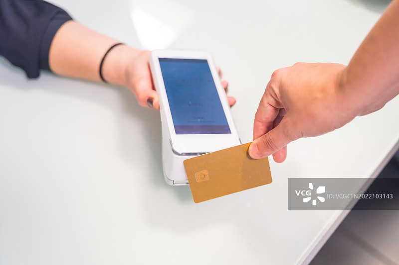 女人用信用卡和POS机进行非接触式支付图片素材