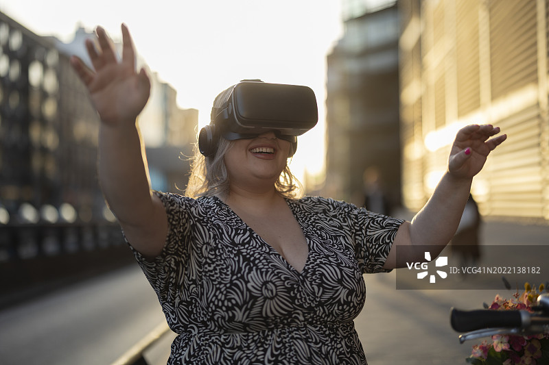 戴着眼镜在城市中使用VR的丰满女人图片素材
