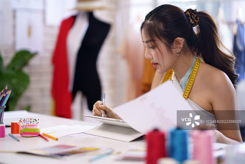 设计师在数字设备上绘制图案模型服装的草图创意图片素材